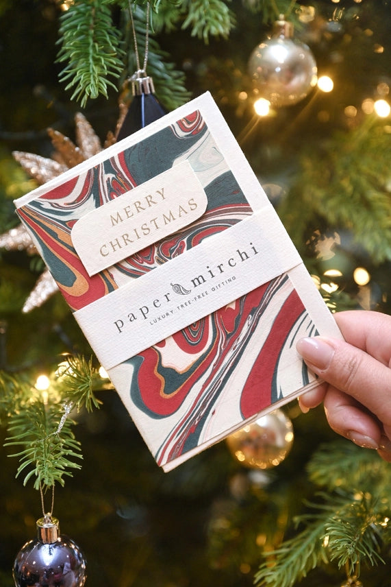 Free Spririt Hand Marbled Christmas Card against a christmas tree 