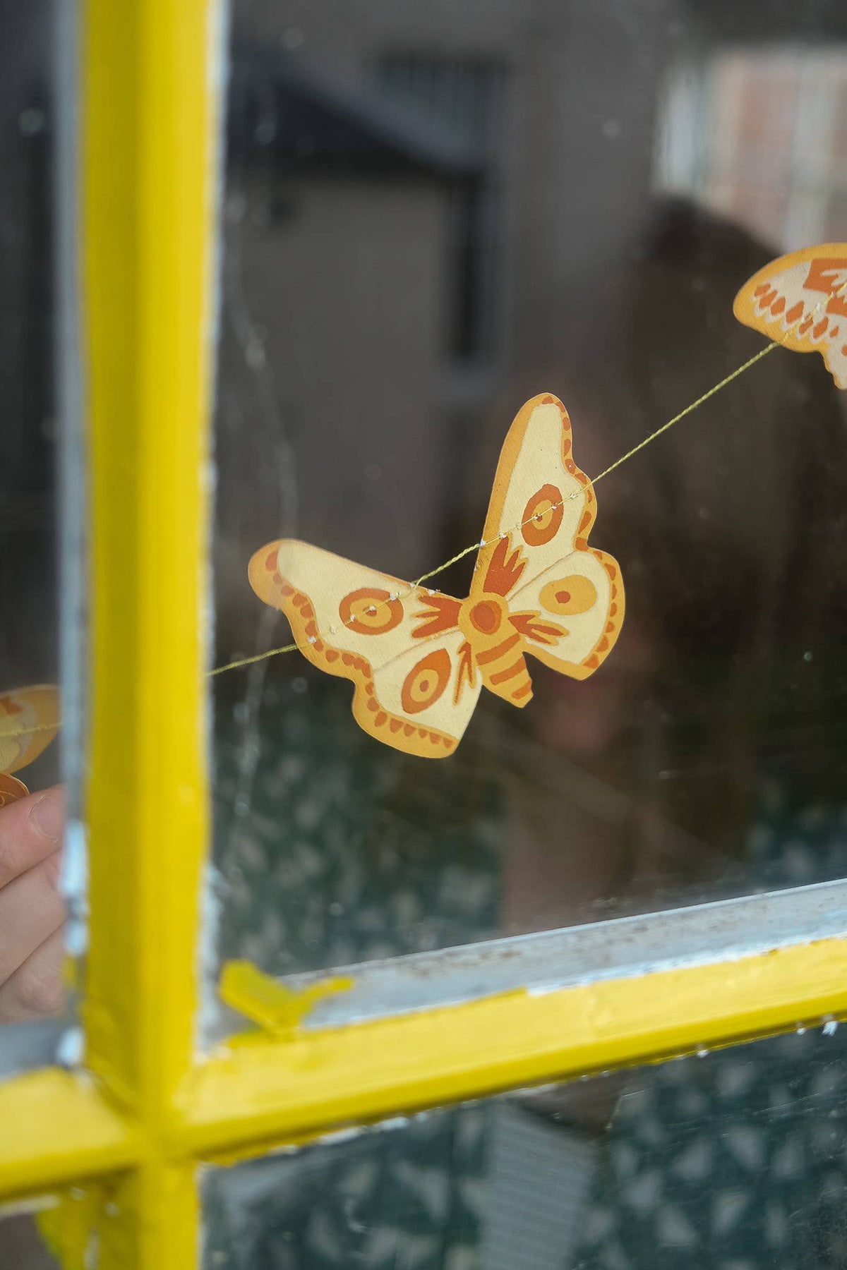 British Butterfly Screen Printed Paper Garland shown in a yellow window frame by east end press at penny black