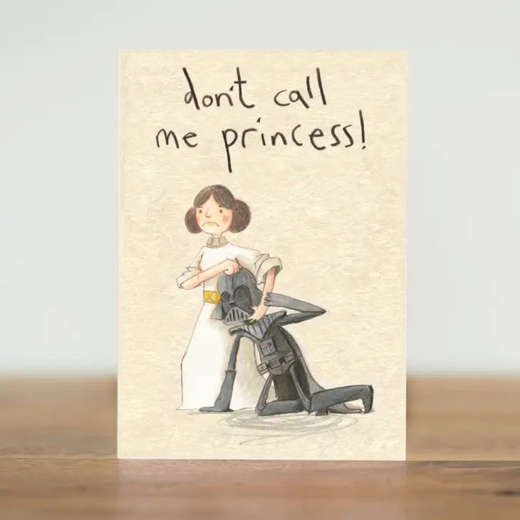 A cream coloured rectangular card with an illustration of Princess Leia with Darth Vader in a headlock. He is on the ground and she&#39;s got her hand around his helmet. Above the image are the handwritten words &#39;Don&#39;t call me princess&#39;